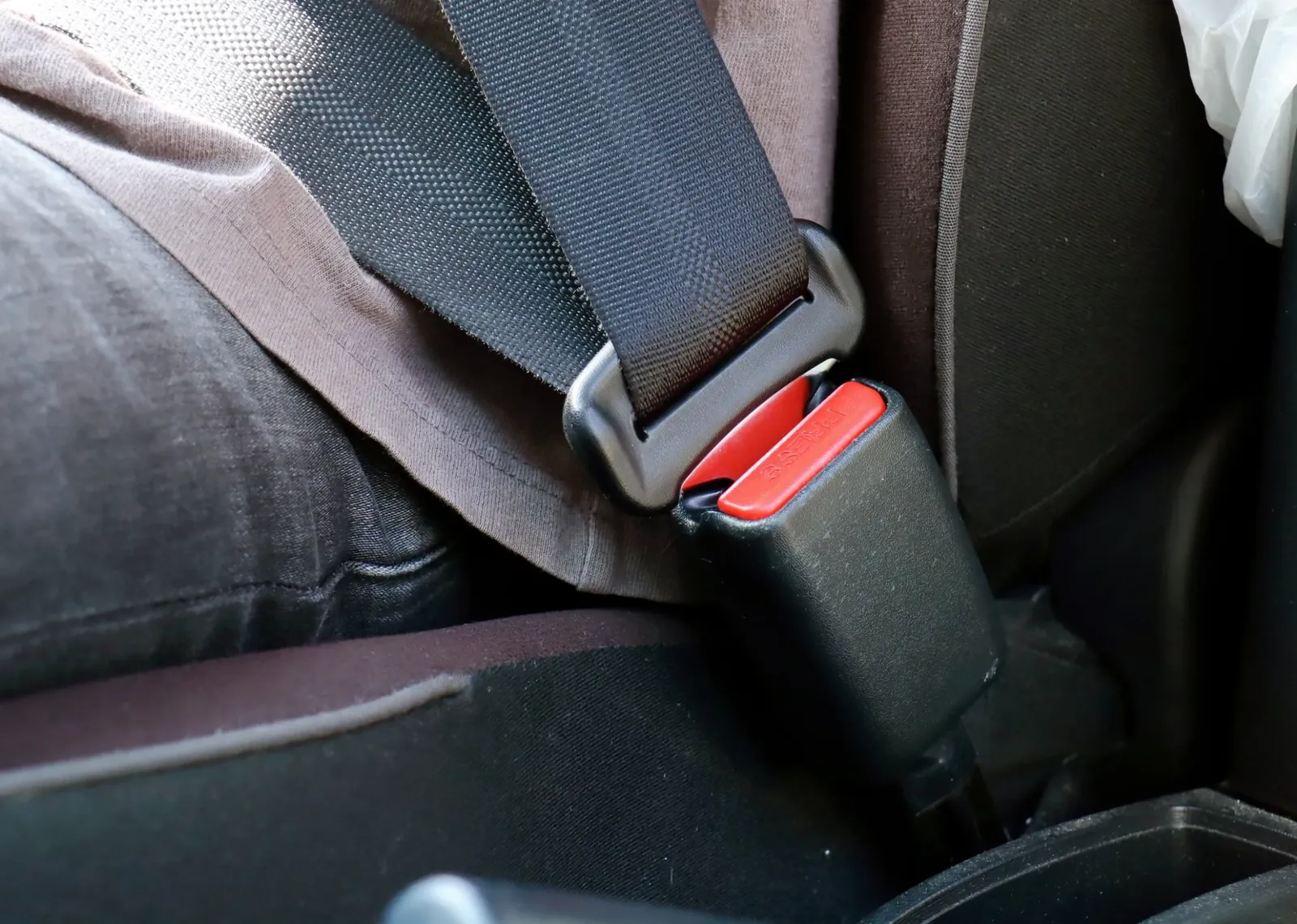 Occupant seated with the seat belt fastened, showing the shoulder and lap sections across the body.